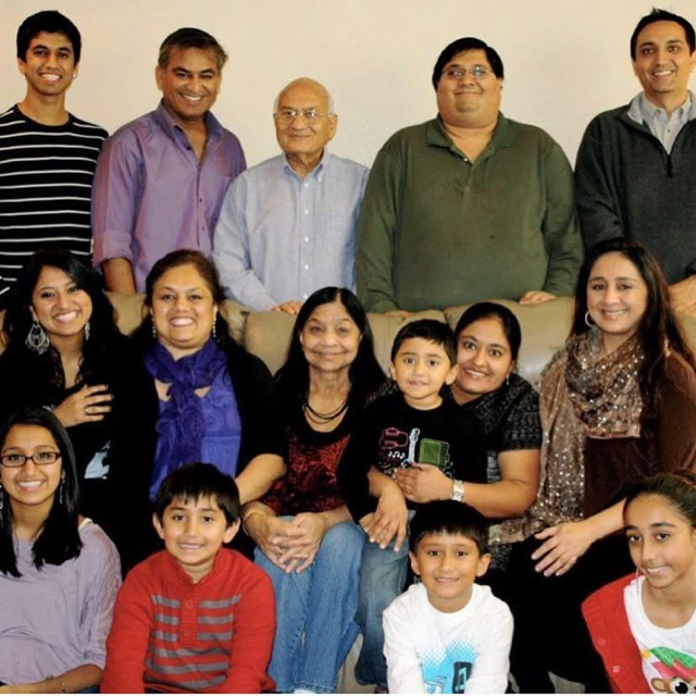 Large family group posing indoors, smiling and seated together in two rows.
