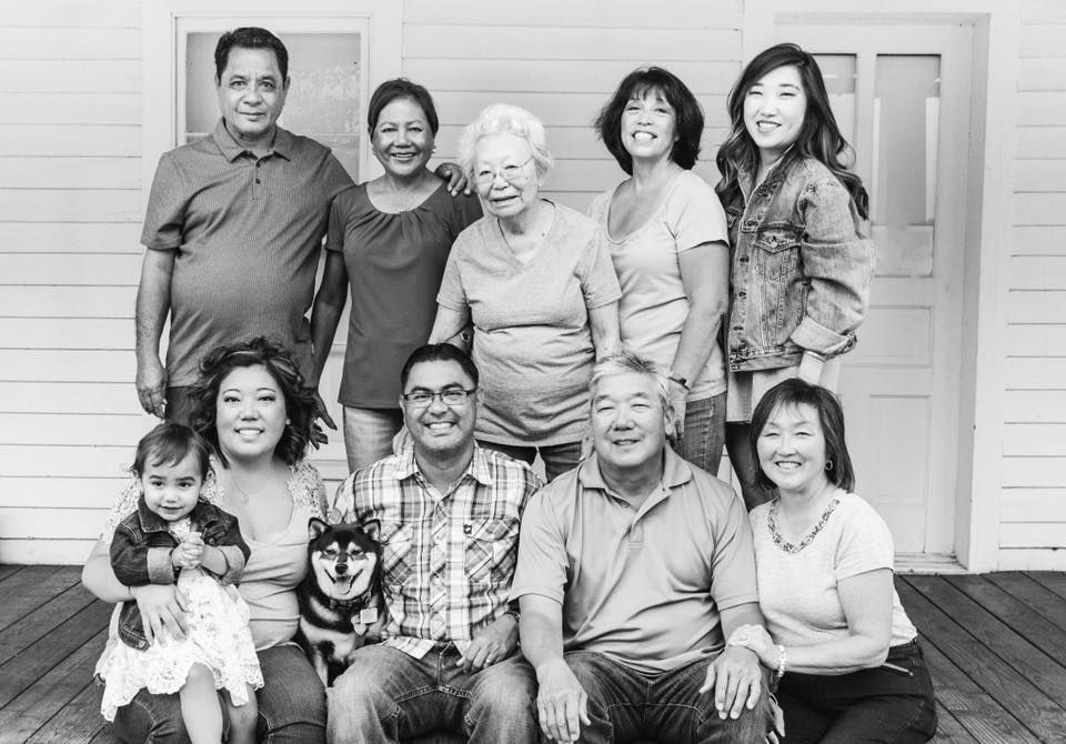 Family portrait of eight people and a dog posed in front of a house garage door