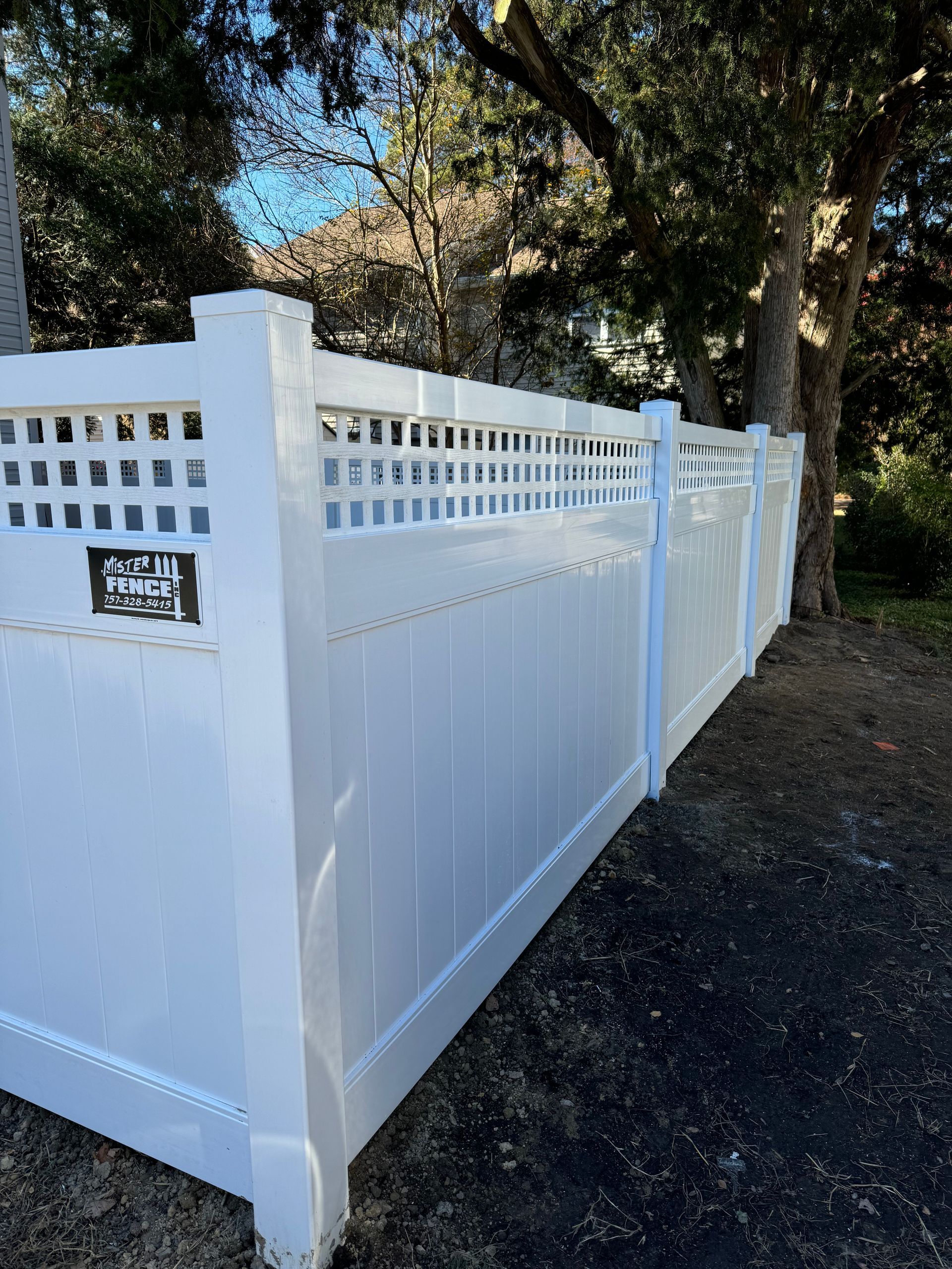 White vinyl fence with lattice top, near a tree.
