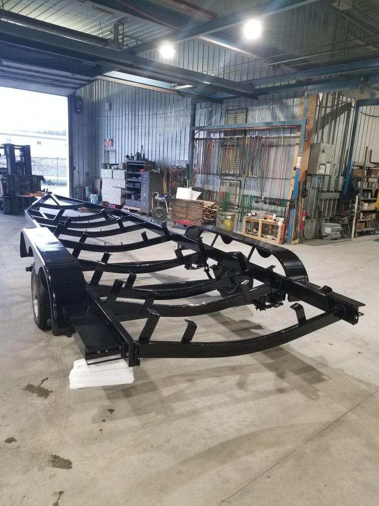 Une remorque de bateau est assise dans un garage à côté d'un chariot élévateur.