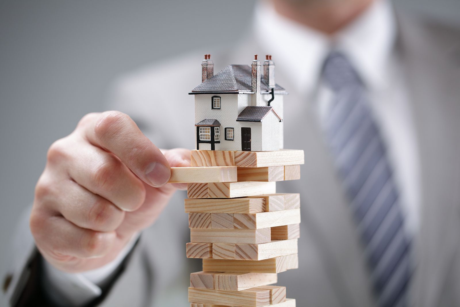 Photo by RattikinLaw in Fort Worth, Texas. The image shows a man playing a jinga puzzle with a house balanced on top.