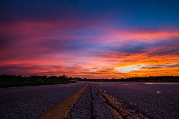 A road with a colorful sunset in the background.