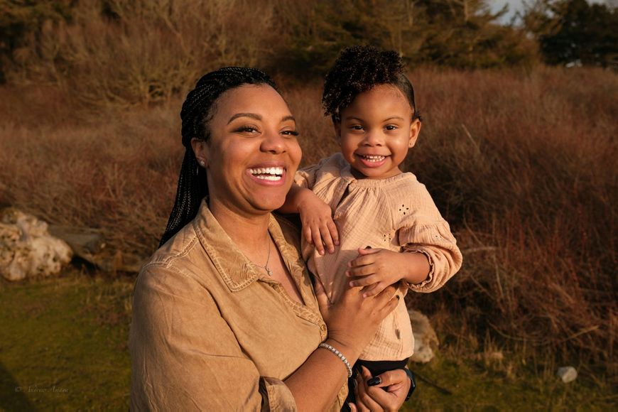 A woman is holding a little girl in her arms and smiling.