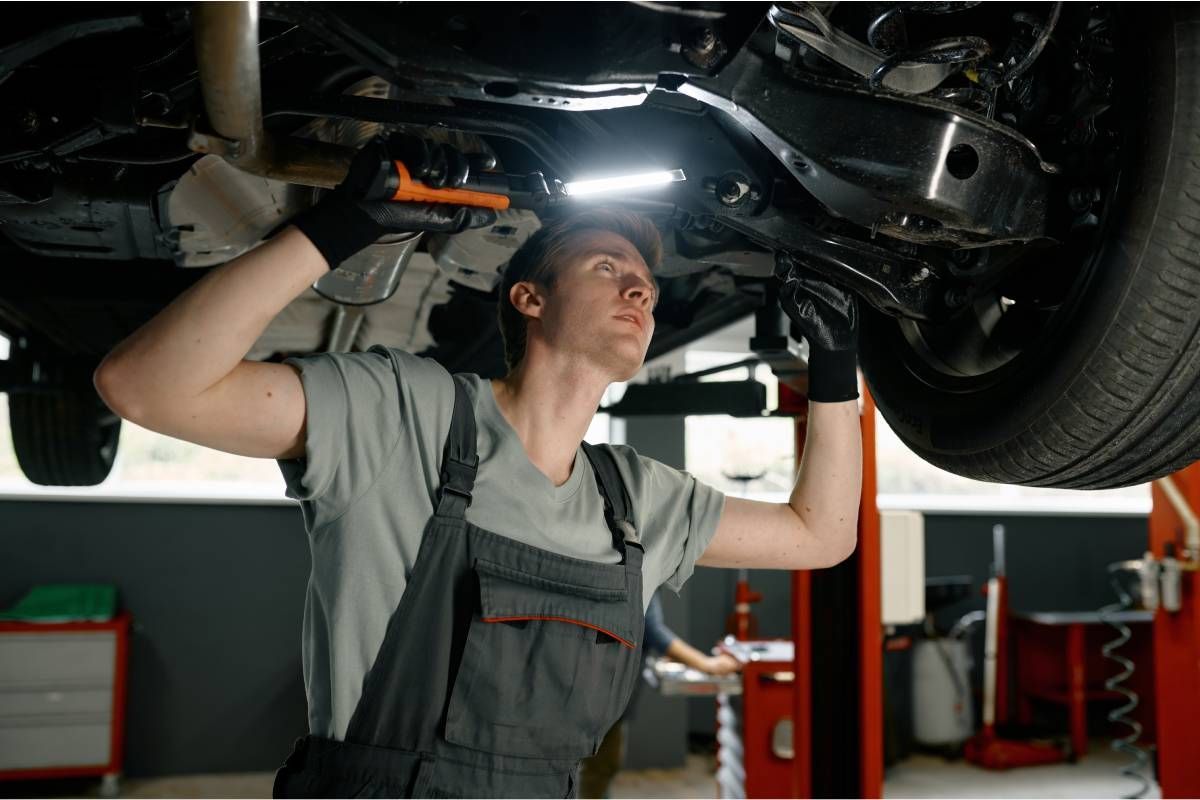 An auto mechanic checks for transmission fluid leaks on a car near Cincinnati, OH