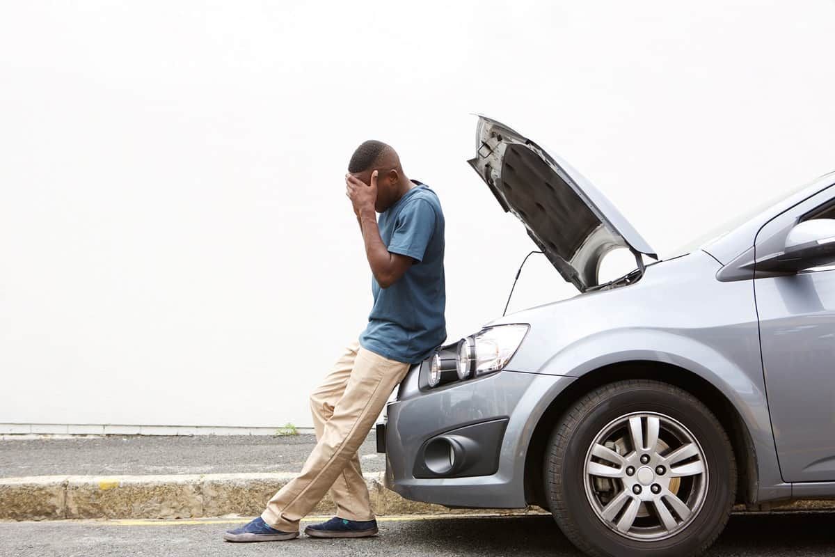 Person sitting on the hood of their broken down car on the side of the road near Cincinnati, OH