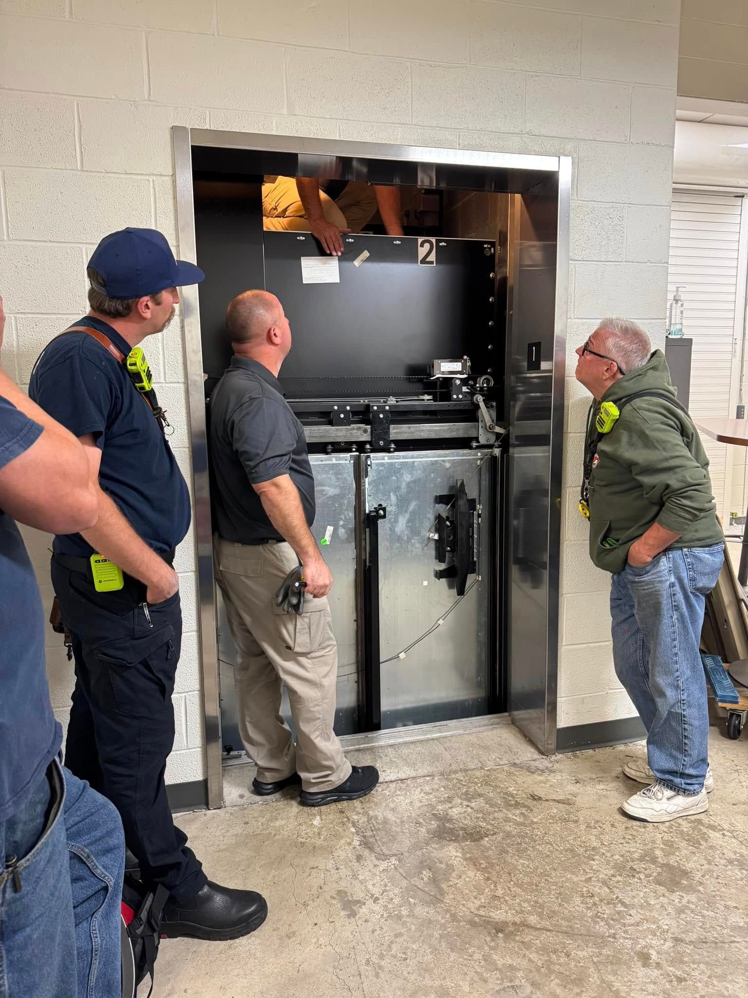 A group of firefighters are standing in front of an elevator for training