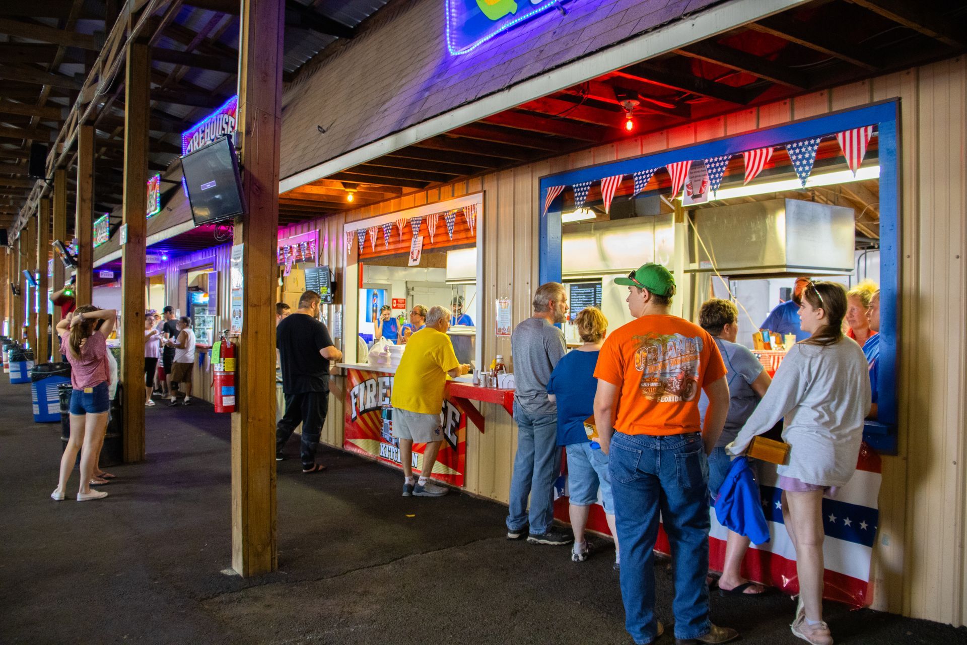 A group of people are standing in line at a food stand.