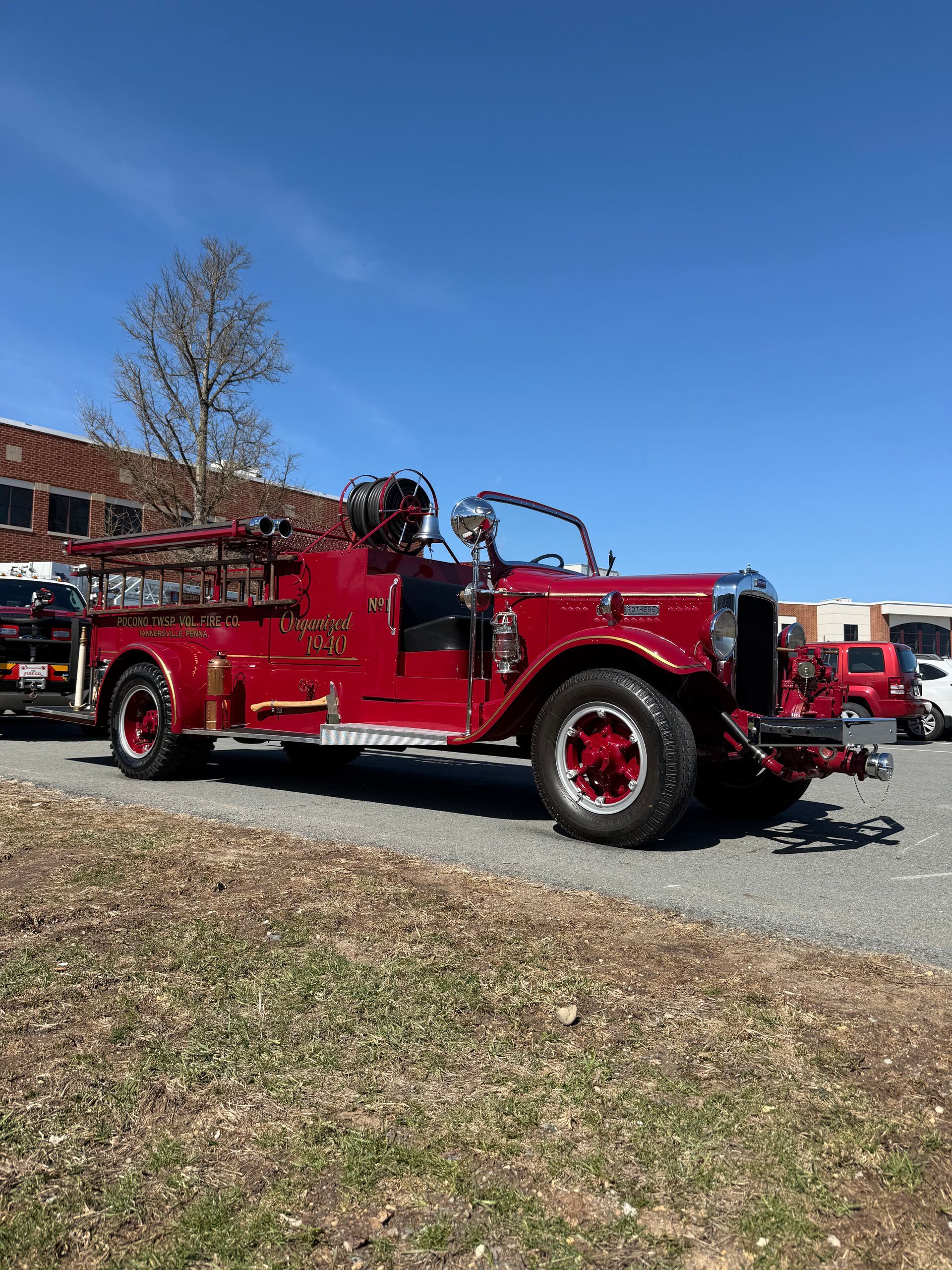 An old red fire truck is parked in a parking lot.