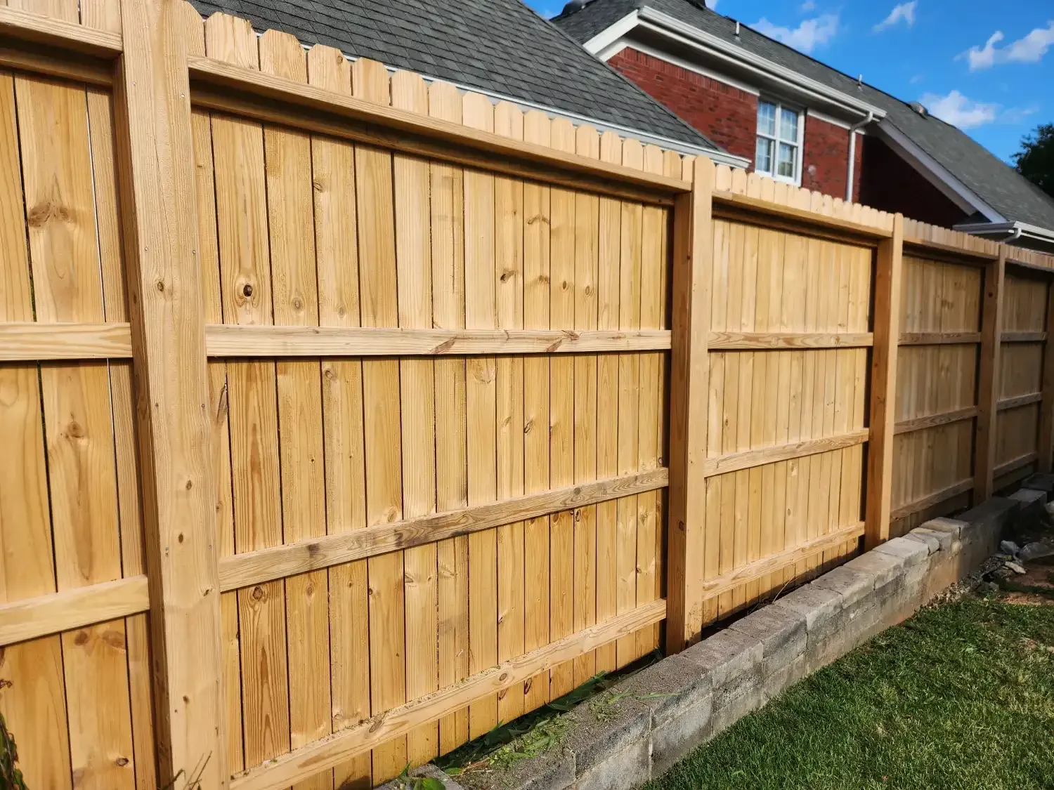 New wooden fence along a grassy yard beside a house