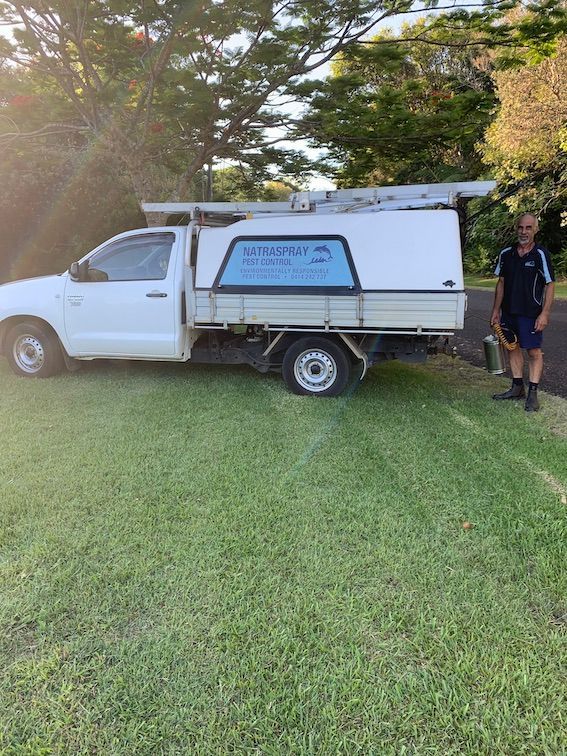 A Man Is Standing Next to A White Truck in A Grassy Field — Natraspray Lismore in Evans Head, NSW