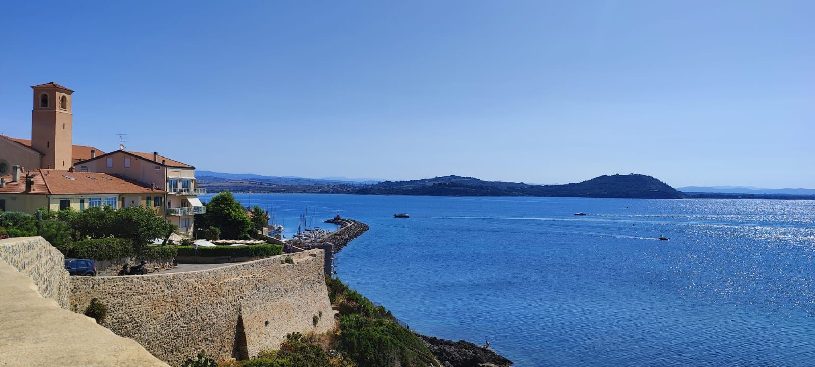 Talamone, a coastal town in Tuscany with fortifications overlooking a vast blue sea.