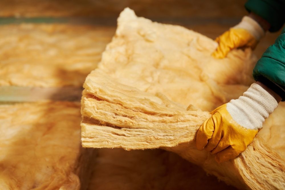 Person in gloves holding a light brown insulation panel.