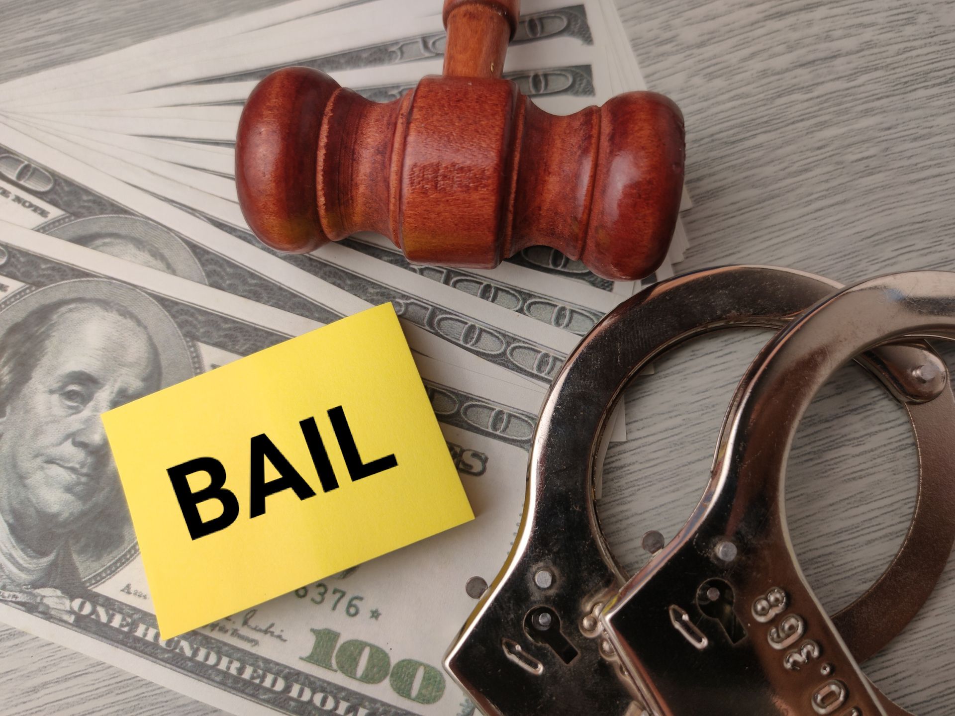 Emergency bail bonds concept featuring gavel, handcuffs, cash, and bail notice on desk. Emergency bail bonds concept featuring gavel, handcuffs, cash, and bail notice on desk.