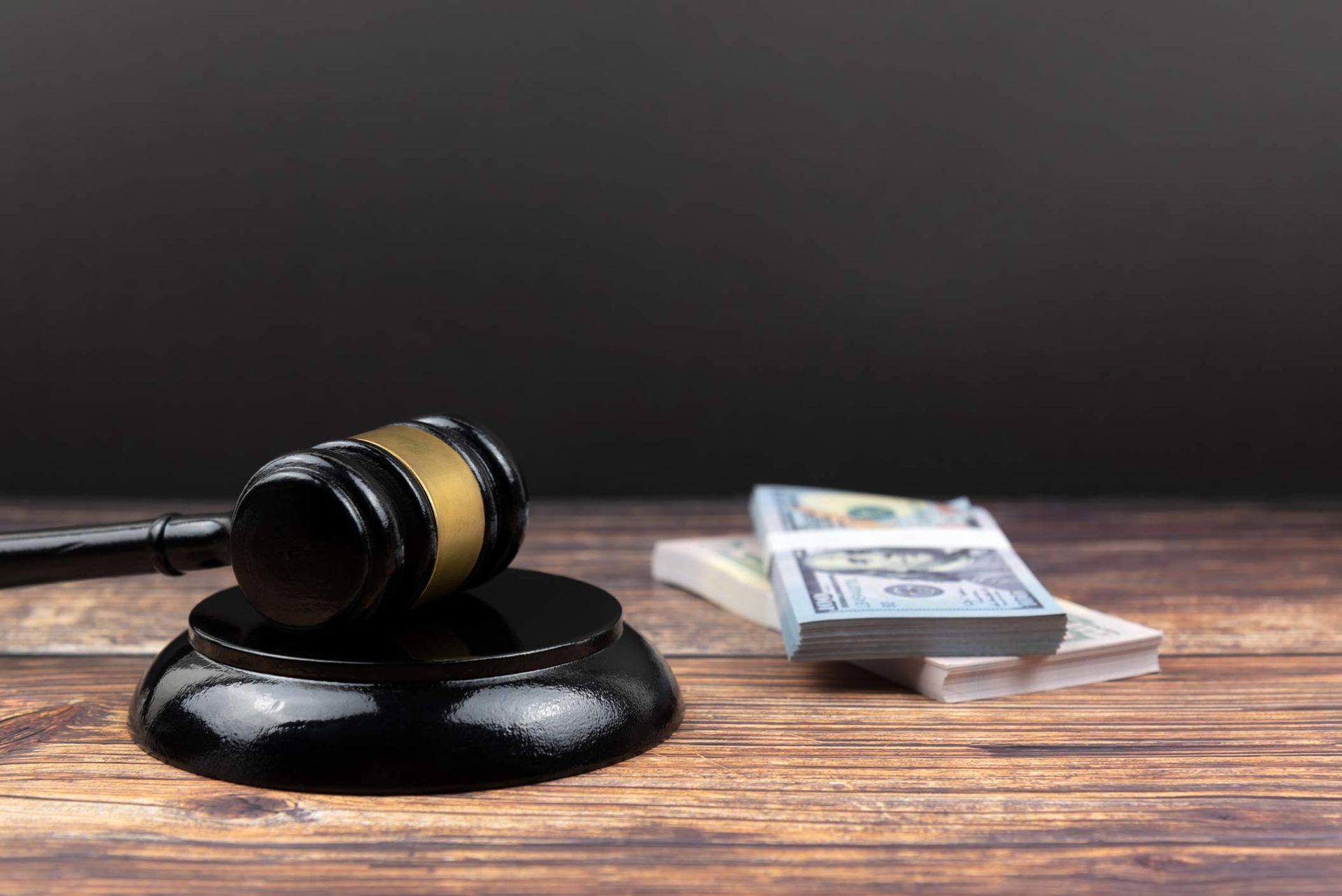 Gavel on table with cash stack in background.