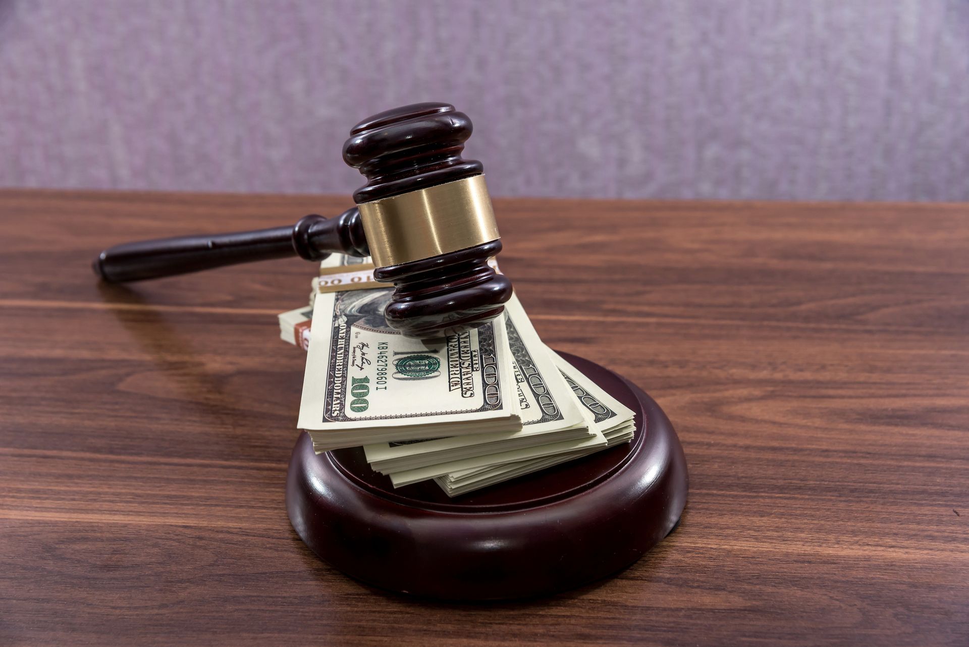 A judge's gavel rests beside stacks of money on a wooden table, symbolizing bail bonds services.