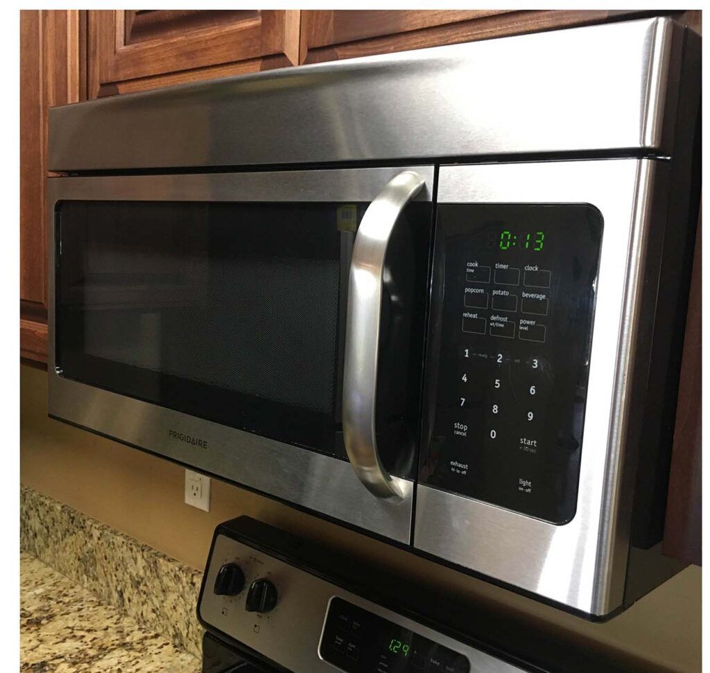 A stainless steel microwave oven is sitting on top of a stove.