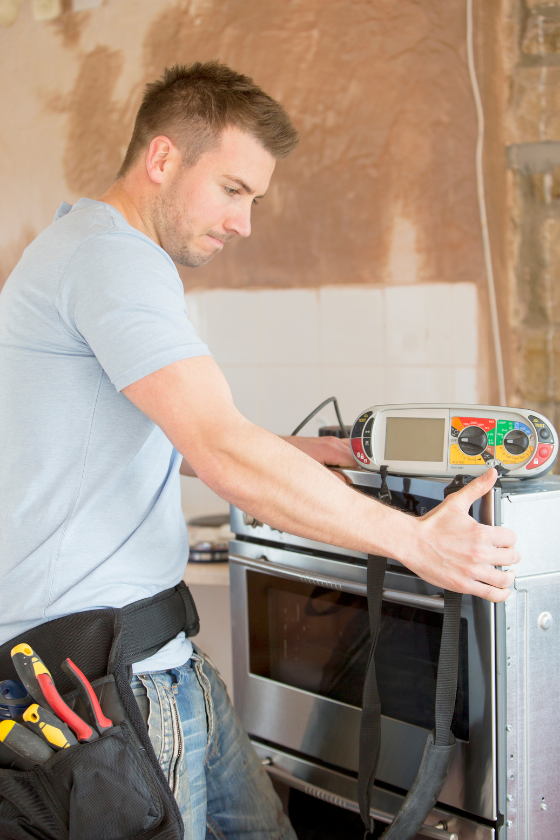A man is working on an oven in a kitchen.
