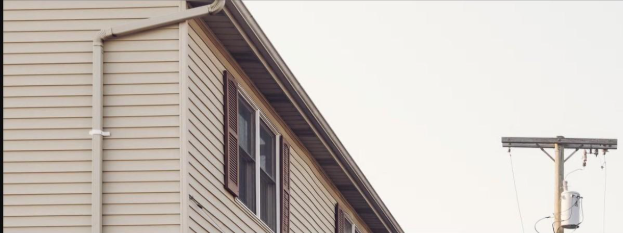 Horizontal vinyl lap siding on a gable end with downspout and shutters, the kind of vinyl siding