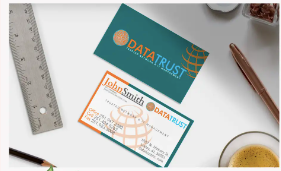 Business cards and desk items on a white surface, featuring teal and orange branding.