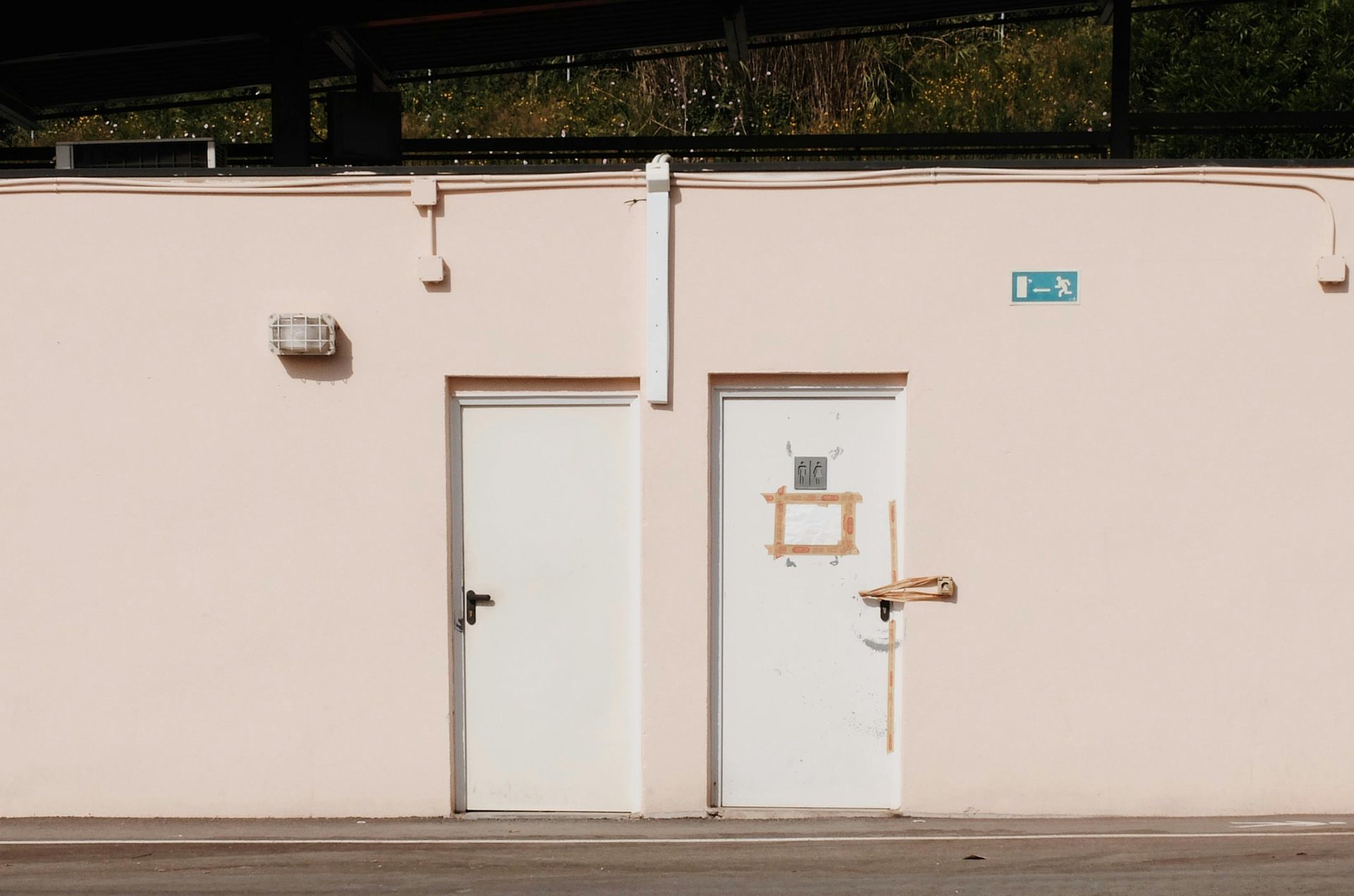 Two white doors set into a peach-colored wall, next to a street.