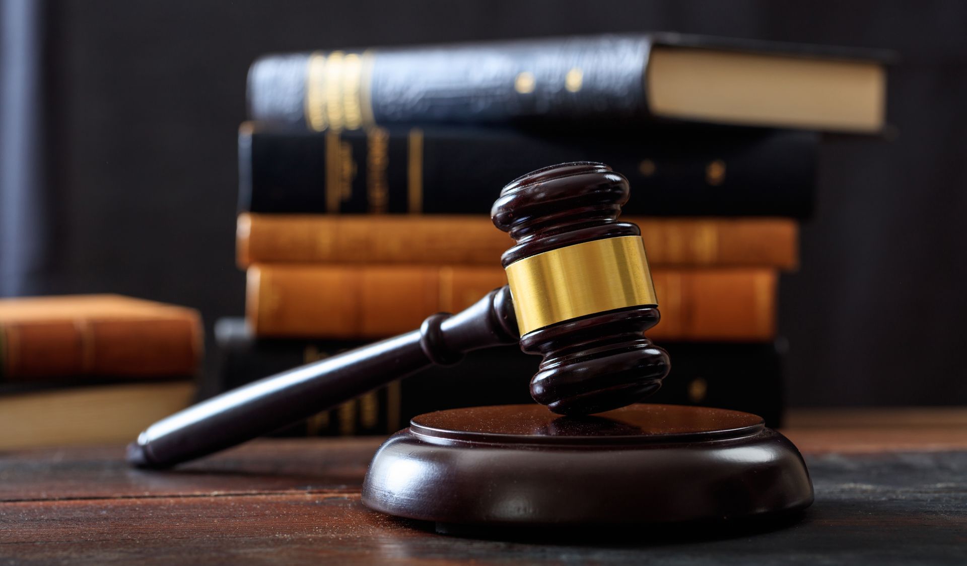 Gavel on sound block in front of stack of law books.