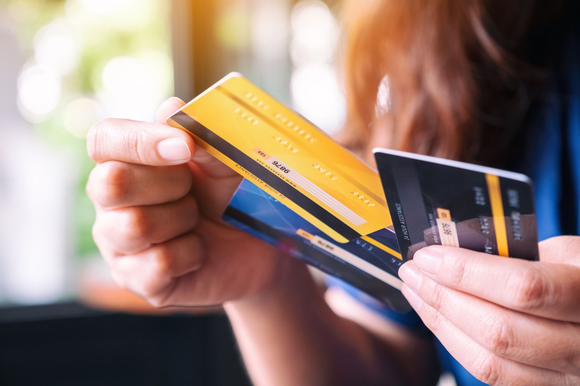 Person holding a stack of credit cards, with a yellow, blue, and black card visible. Person holding a stack of credit cards, with a yellow, blue, and black card visible.