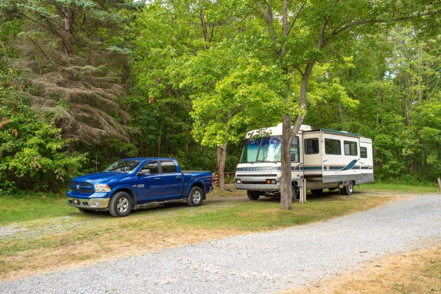 a blue truck is parked in front of an RV in a forest