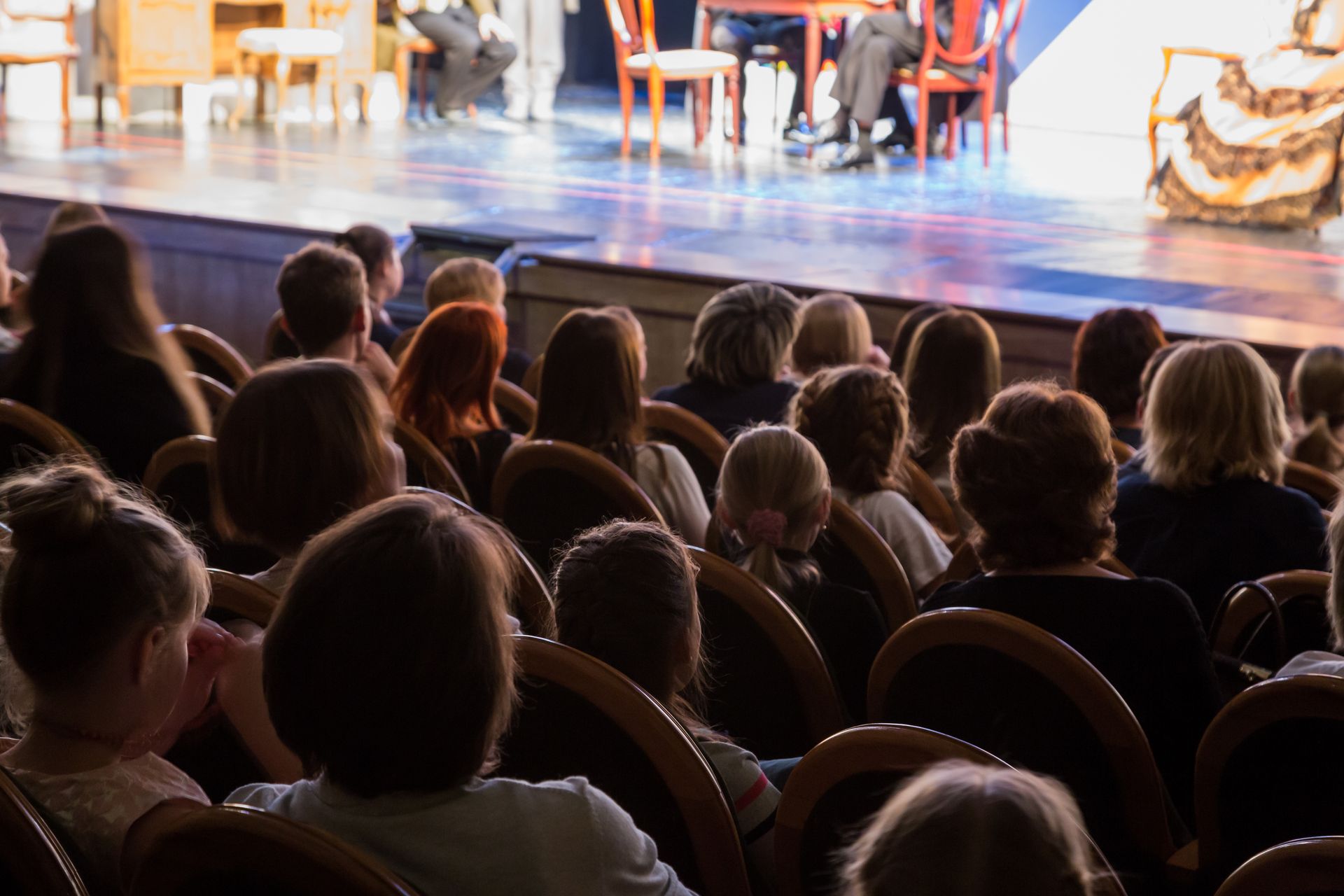 A large group of people are sitting in a theater watching a play.