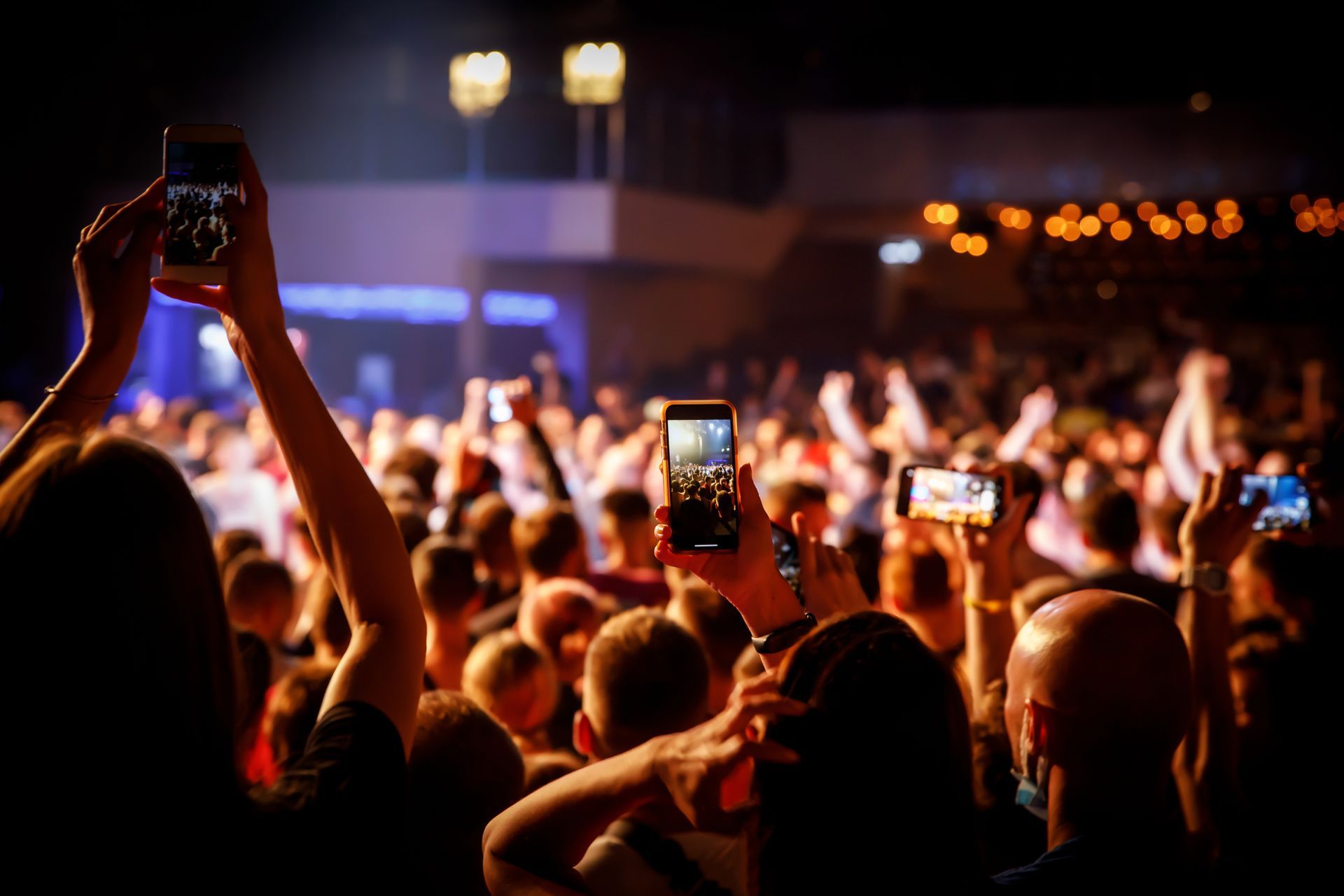 A crowd of people are taking pictures of a concert with their phones.
