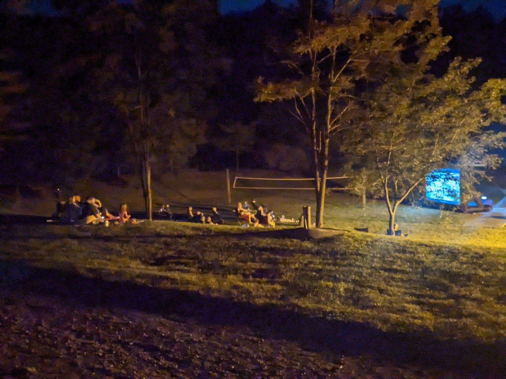 A group of people are sitting around a campfire at night.