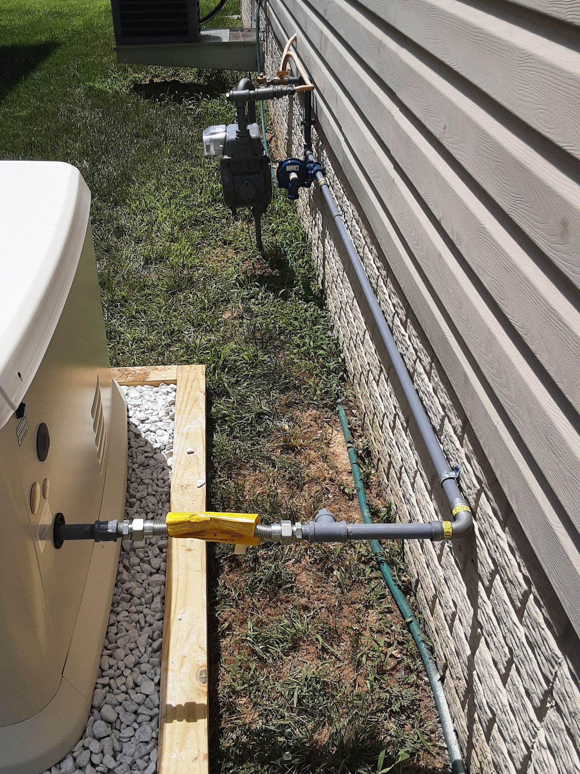 A generator installed outdoors, with gas lines running from the house wall to the unit.