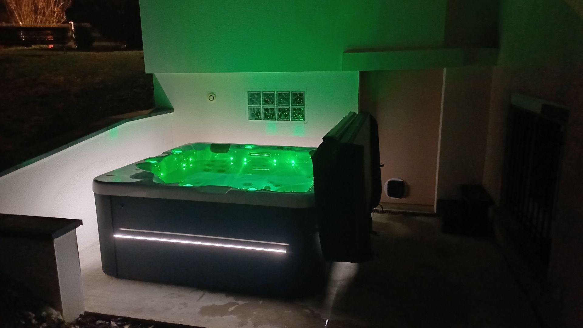 Un jacuzzi avec des lumières vertes est assis dehors la nuit.