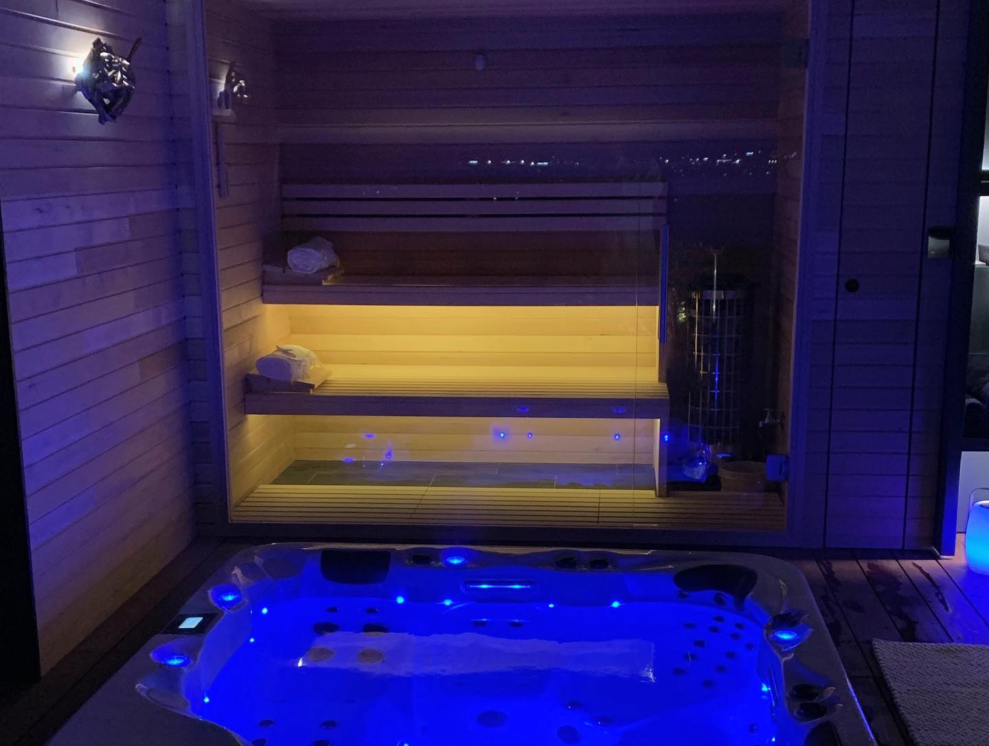 Un bain à remous est placé à côté d'un sauna dans une pièce.