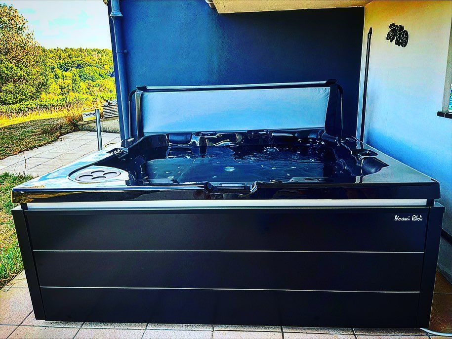 Un grand jacuzzi noir avec le couvercle ouvert