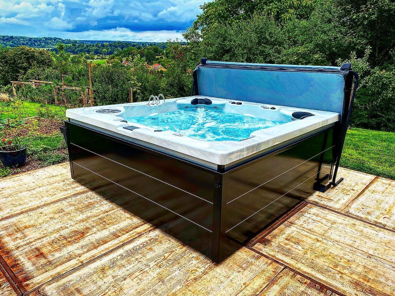 Un bain à remous est installé sur une terrasse avec des arbres en arrière-plan.