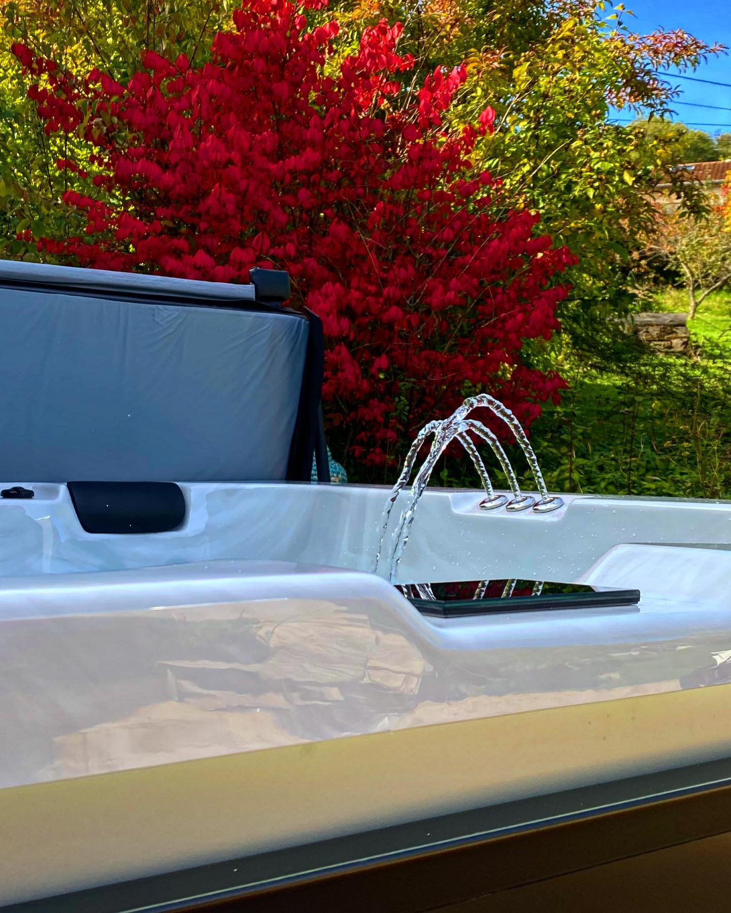 Un jacuzzi blanc est assis devant un arbre rouge.