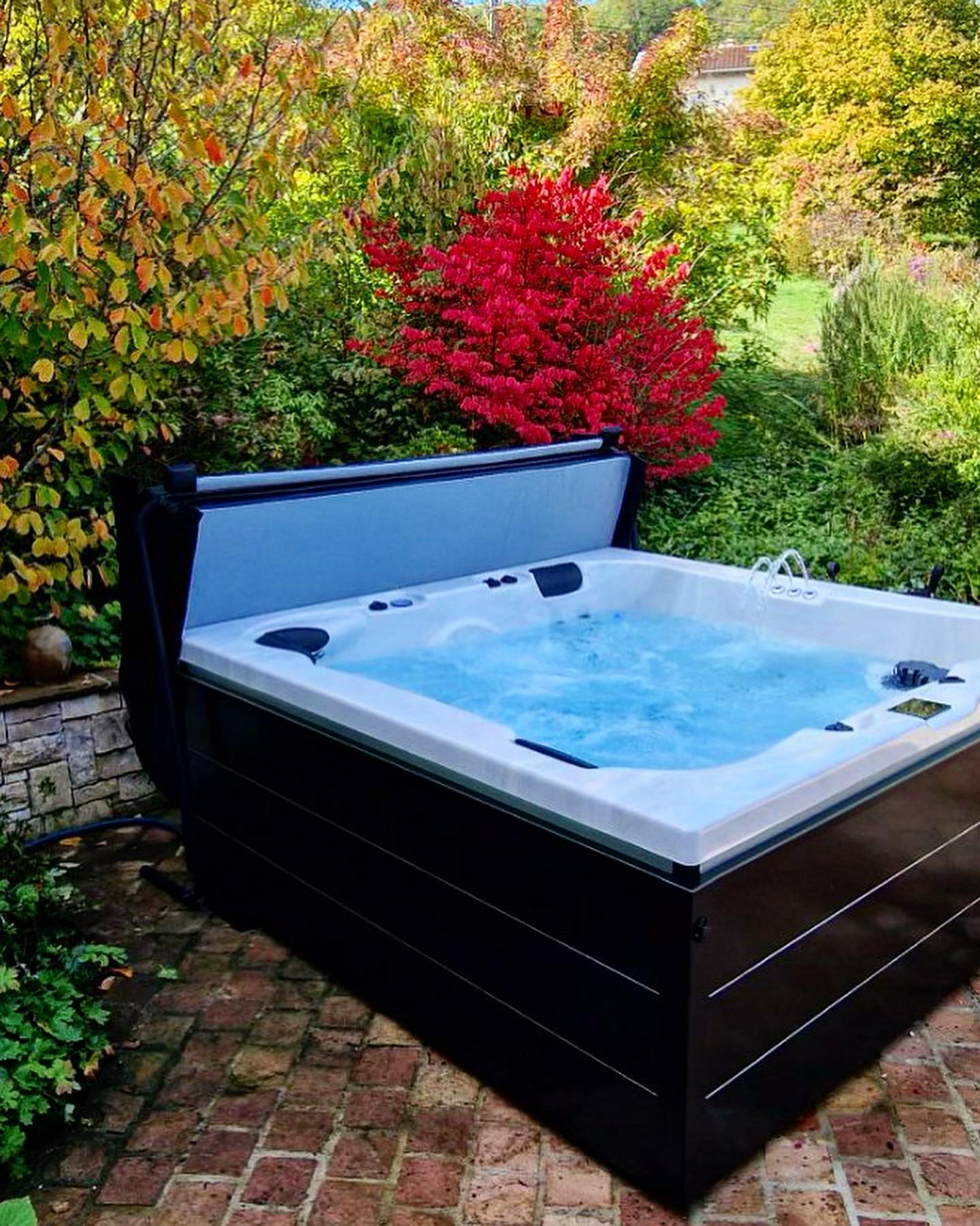 Un bain à remous est installé sur un patio en briques dans un jardin.