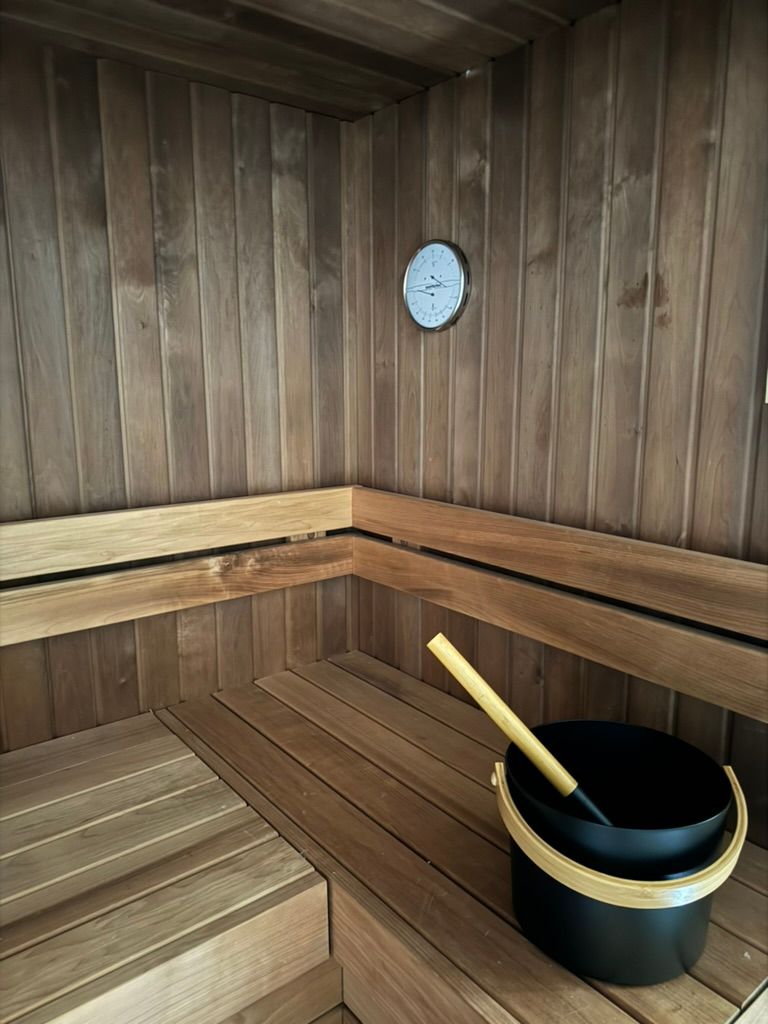 Un sauna en bois avec un seau et un thermomètre au mur.