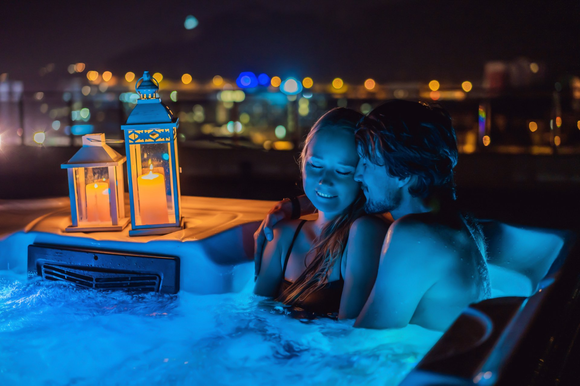 Un homme et une femme sont assis dans un bain à remous la nuit.