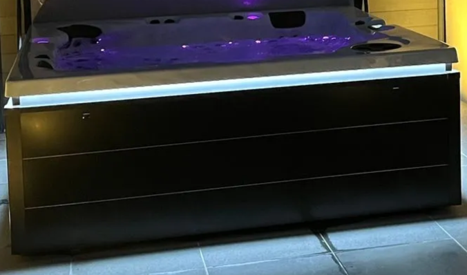 Un jacuzzi noir et blanc avec des lumières violettes dessus