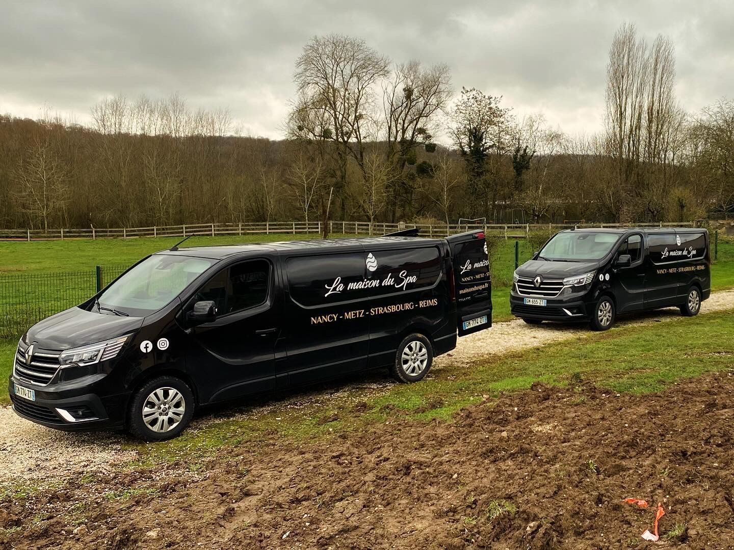 Deux camionnettes noires sont garées l'une à côté de l'autre dans un champ.