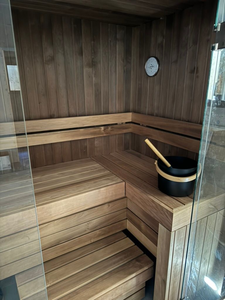 Un sauna en bois avec un seau et une horloge au mur.