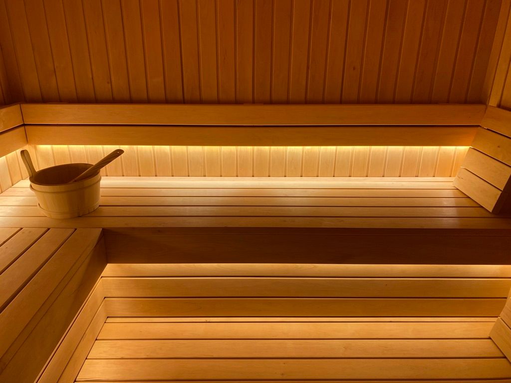 Un sauna en bois avec un seau et une cuillère sur le banc.