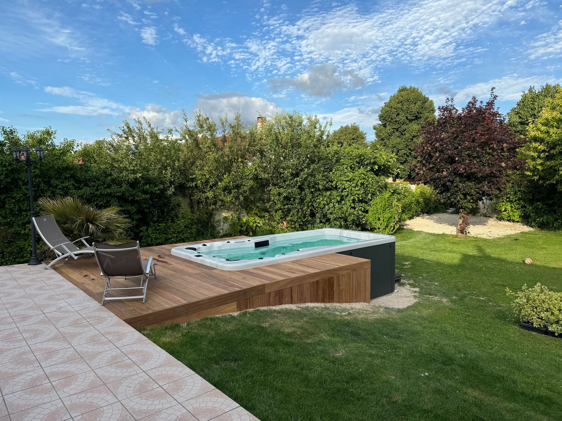 Un bain à remous est posé sur une terrasse en bois dans une cour arrière.