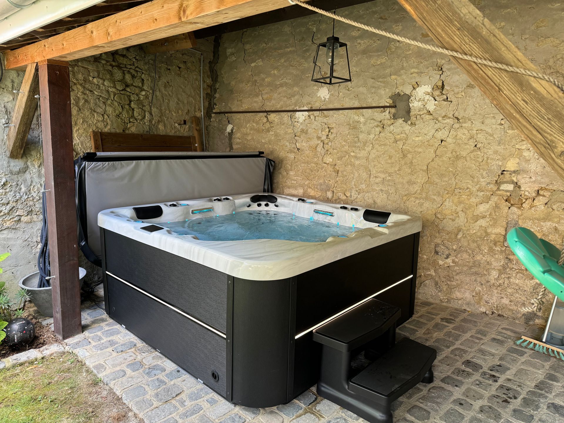 Un jacuzzi noir et blanc est assis sous un toit.