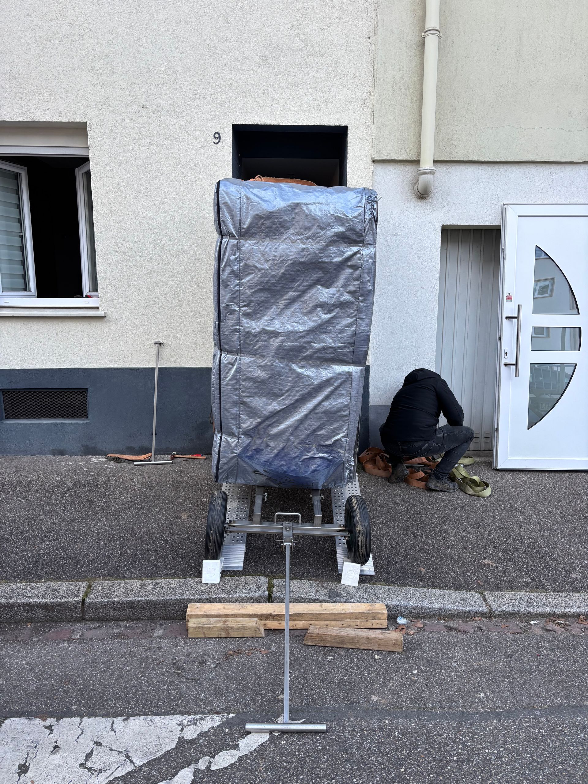 Un homme est assis sur le trottoir devant un bâtiment.