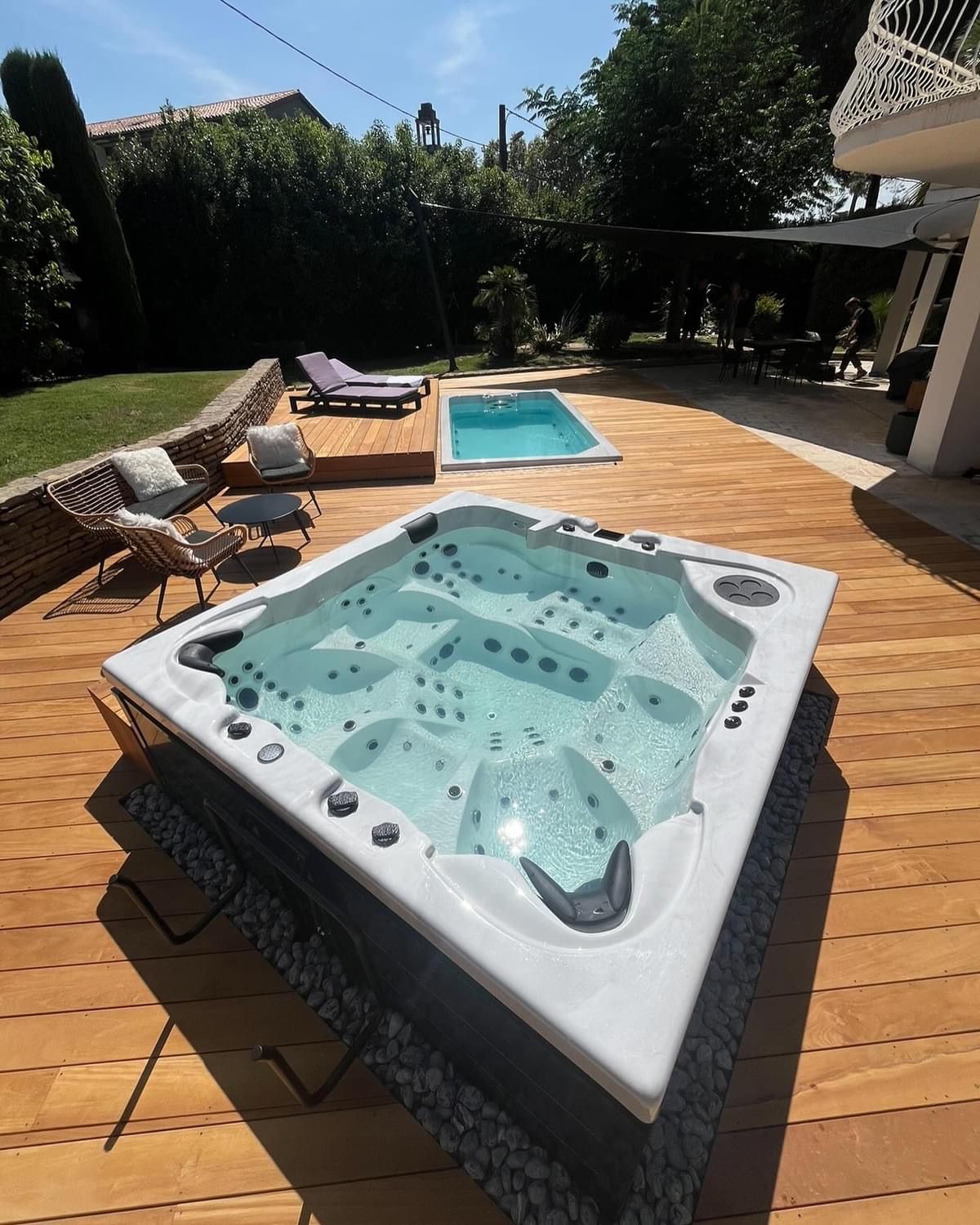 Un bain à remous est installé sur une terrasse en bois à côté d'une piscine