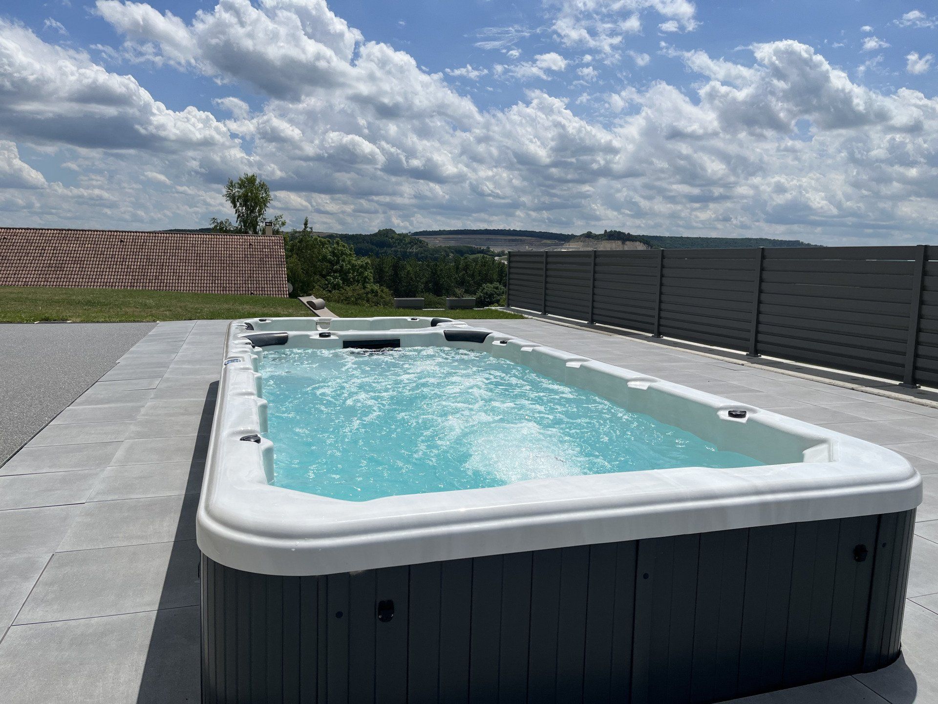 Une grande piscine est située sur un patio à côté d'une clôture.