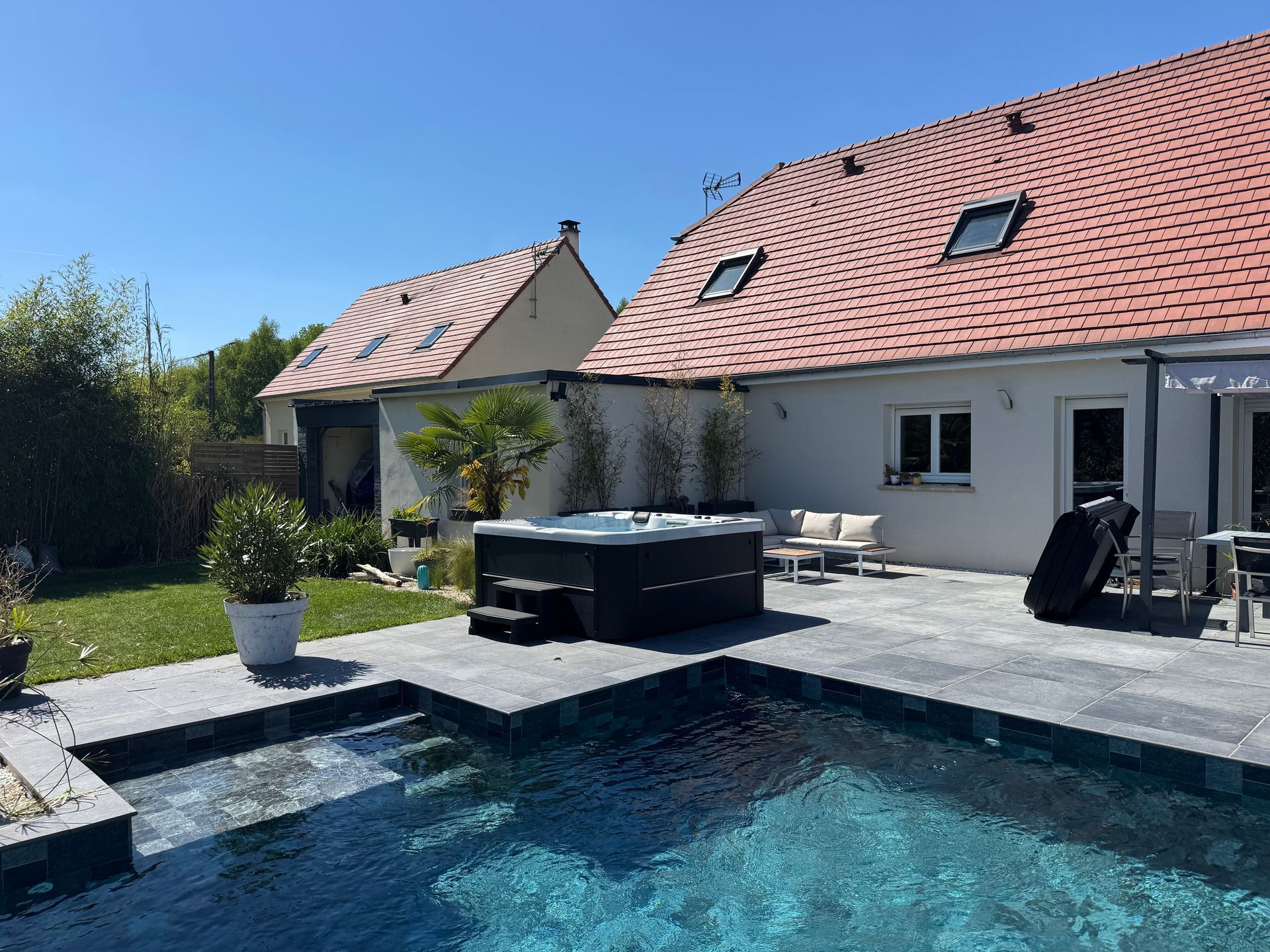 Une maison avec une piscine et un jacuzzi devant