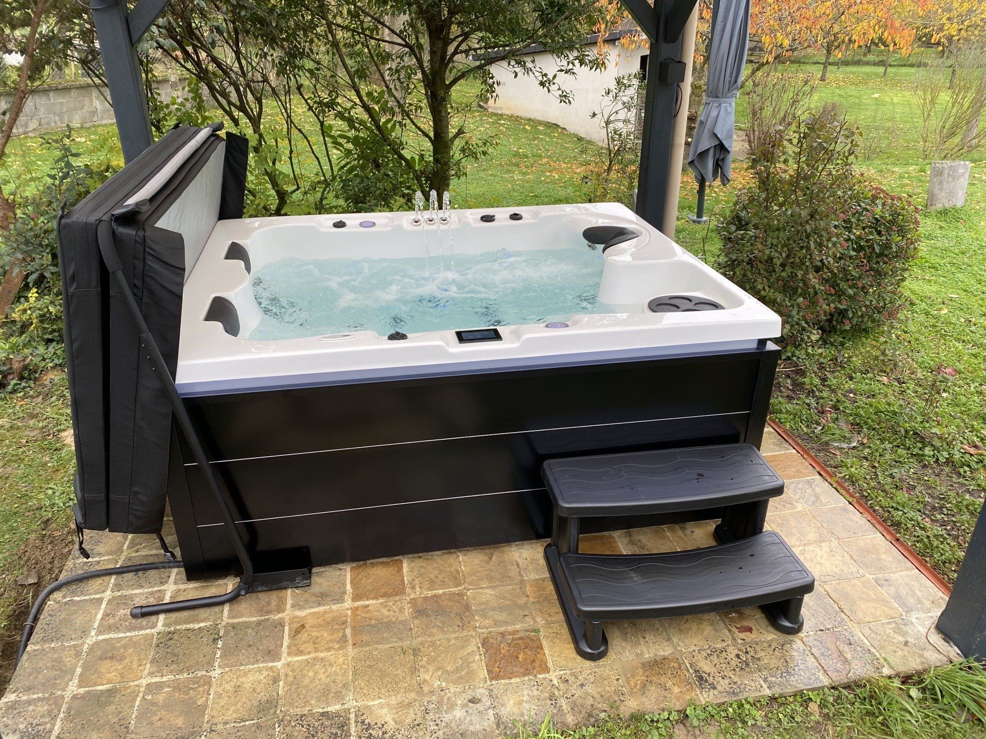 Un jacuzzi noir et blanc avec des escaliers assis sur une terrasse.
